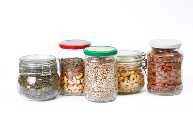 Nuts and seeds in jars on white background