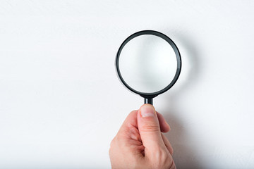 Magnifier in a man's hand on a white background. Close up