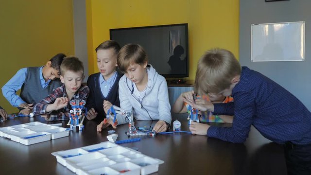 Children in the classroom make figures with teacher. Modern technology concept