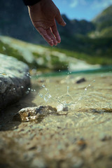 Stone falling down from hand in the water