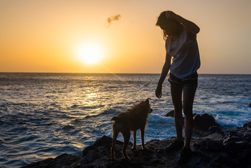 girl with her dog at sunset on the sea
