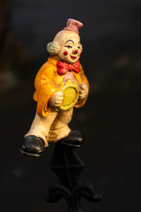 Fröhliche Clownsfigur als Spielzeug mit einem Lächeln im Gesicht auf einen Zaun aufgesteckt in Seitenansicht