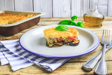 Delicious meat casserole with eggplant, minced meat, tomato, bechamel sauce and cheese. Greek moussaka on rustic wooden background. Selective focus