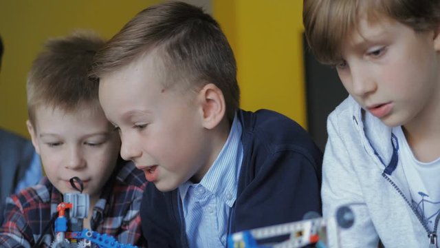 Children in the classroom make figures with teacher. Modern technology concept