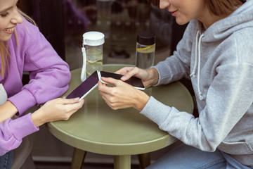 Positive delighted girls staring at their smartphones