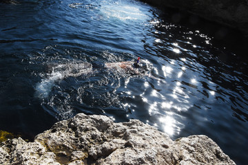 Glare of the sun on the surface of the sea, a man swims in a mask.