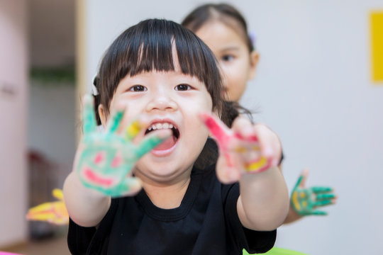 Asian little girl shows painted hands with her friend