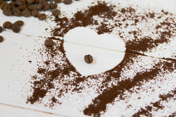 Heart made of instant coffee. Ground coffee and whole coffee beans on a white background.