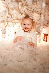 Fototapeta premium girl in Christmas decorations with artificial snow and small cardboard houses