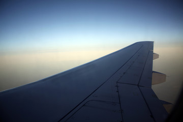 Fototapeta na wymiar Wing of an airplane flying above the clouds. Travelling concept
