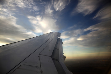 Wing of an airplane flying above the clouds. Travelling concept