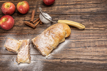 Traditional apple strudel with powdered sugar on wooden rustic background