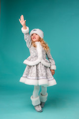 little blonde girl smiling in snow maiden costume isolate on blue background, baby catches snowflakes