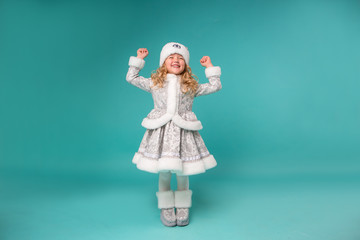little blonde girl smiling in snow maiden costume isolate on blue background, baby catches snowflakes