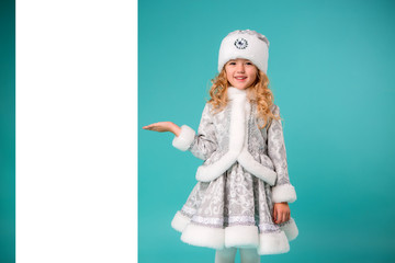 little blonde girl smiling in snow maiden costume isolate on blue background, baby catches snowflakes