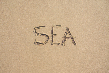 Word SEA drawn on the sand of sandy beach.