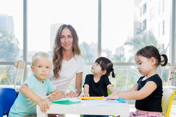 Fototapeta premium Happy teacher and her students make paper crafts