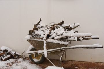 Wheelbarrow filled with snow-covered firewood