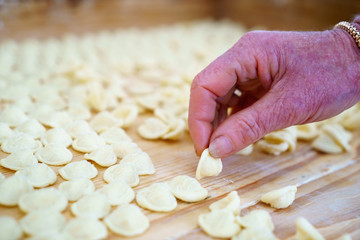 Hands making orecchiette pasta, typical of Apulia, a region of Southern Italy. Their name comes from their shape, which resembles a small ear.
