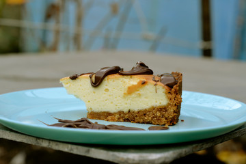 Delicious classic cheesecake with cottage cheese and chocolate sauce on a blue plate 