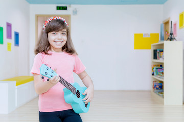 Little girl playing a guitar in the kindergarten