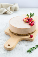 Raw chocolate cake decorated with raspberries and rosemary on a wooden board. Gluten free, vegetarian food.