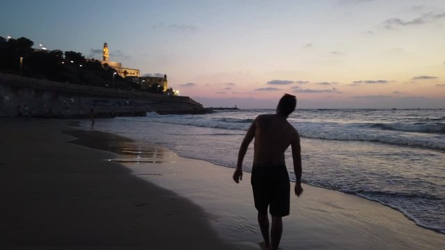 Couple playing frisbee at sunset at Jaffa beach in Tel Aviv-Yafo, Israel, lifestyle and holiday 4k video footage