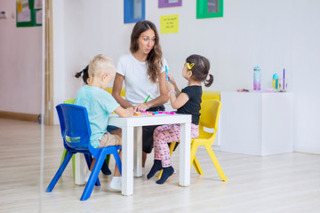 Preschool kids draw on the table with their teacher