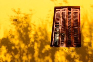 red window on yellow wall with shadows