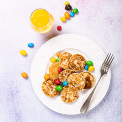 Dutch mini pancakes called poffertjes with colorful candies. Healthy food concept, flat lay, top view, copy space.