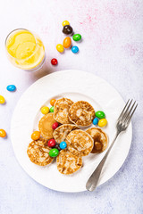 Dutch mini pancakes called poffertjes with colorful candies. Healthy food concept, flat lay, top view, copy space.