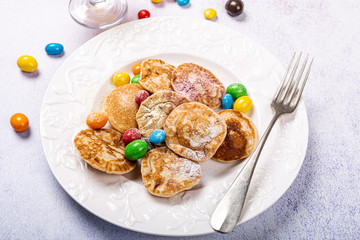 Poffertjes. Little Dutch Homemade pancakes with colorful powdered sugar and candies. Healthy food concept, high angle view.