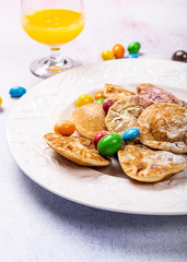 Dutch mini pancakes called poffertjes with colorful powdered sugar and candies. Healthy food concept