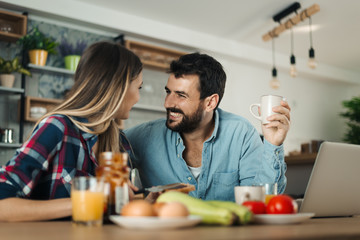  Happy young couple talking to each other while having breakfast in the morning
