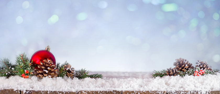 Panoramic view of fir branches and christmas ball on snowy wooden table
