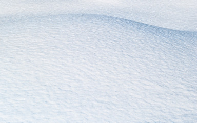 A wave pattern snow drift cuts across a field with bright white new fallen blanket of snow
