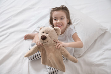 Cute little girl in bed with soft toy.