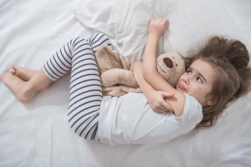 Cute little girl in bed with soft toy.