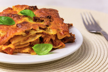 Lasagne with basil leafs served on a white plate