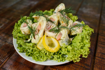 Tasty and fresh pancakes with pink salmon on a large white plate on a wooden table