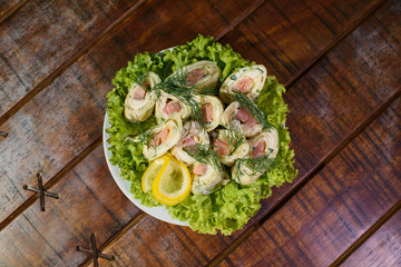 Tasty and fresh pancakes with pink salmon on a large white plate on a wooden table