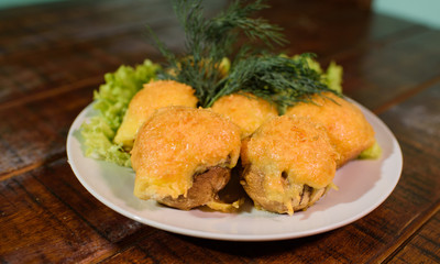 Beautiful stuffed champignons on a large white plate on a large wooden table