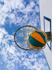 Basketball in the hoop and blue sky above