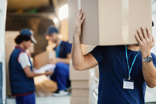 Unrecognizable manual worker unloading boxes from a delivery van.