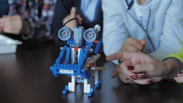 Children in the classroom make figures with teacher. Modern technology concept