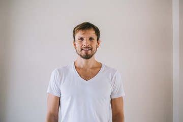 Half length portrait of positive guy enjoying free time posing on promotional background near wall, handsome prosperous man in t-shirt with copy space for brand name or label looking at camera