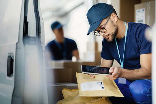 Male deliverer scanning bar code on a package with a touchpad.