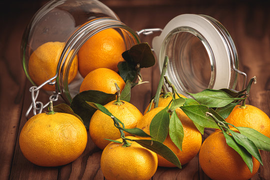 tangerines and glass jar on wooden surface