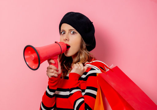 Young woman with shopping bags and loudspeaker on pink background - Powered by Adobe