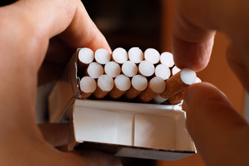 close up person's hand pick a cigarette from the carton pack box